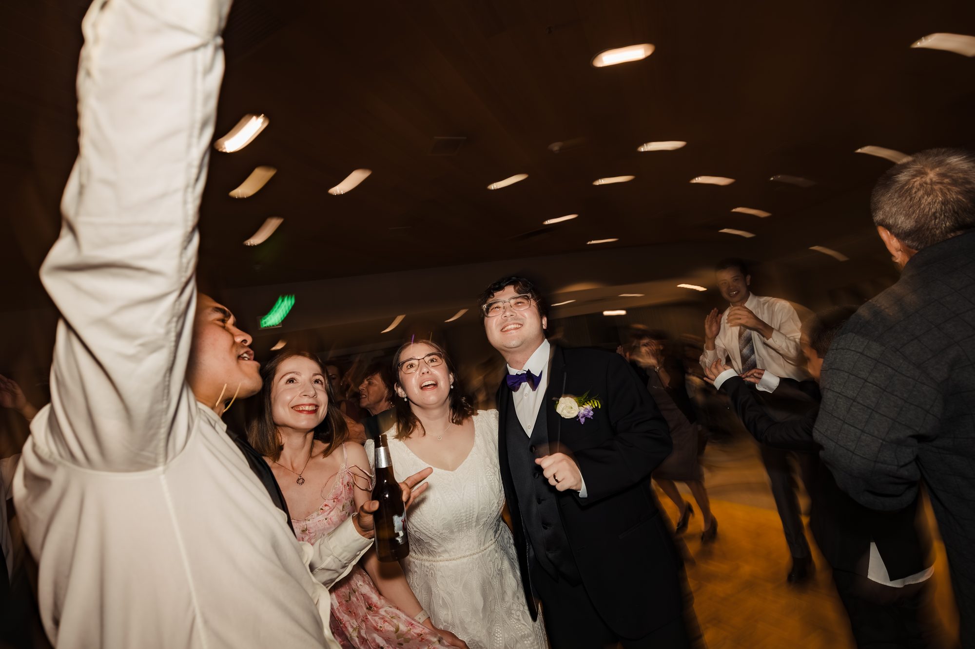 Bride and groom surrounded by friends celebrating on the dance floor