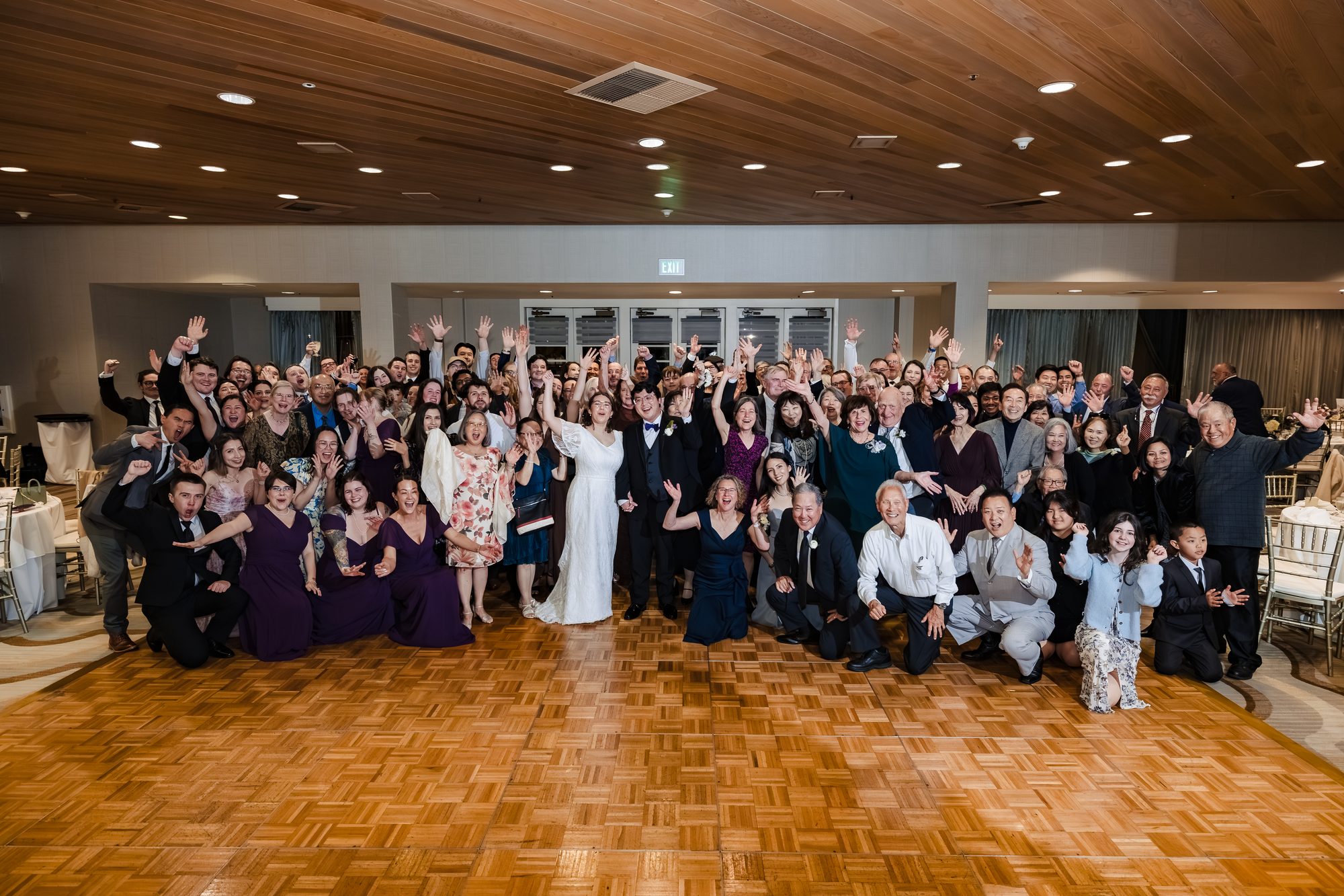 Large group photo of all the guests with the bride and groom on the dance floor at the Sonesta ballroom