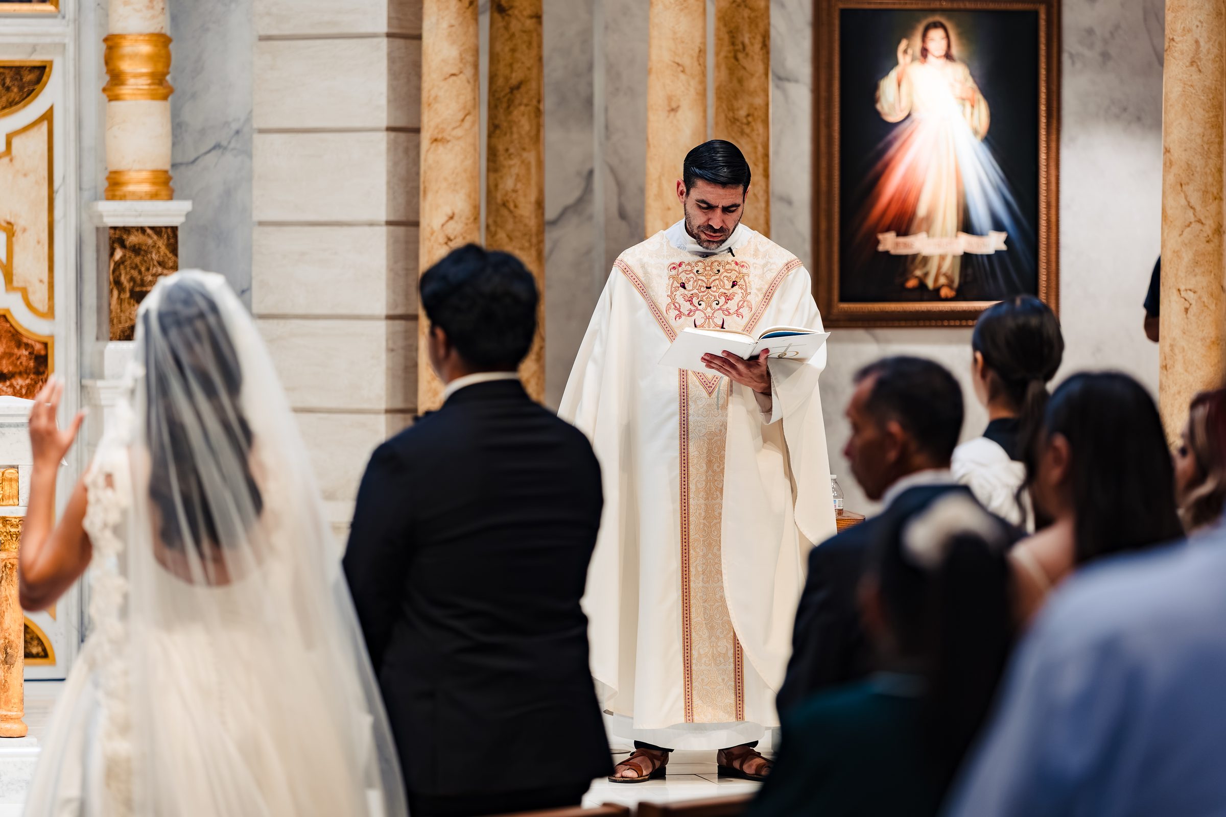 The priest reading before the image of Divine Mercy