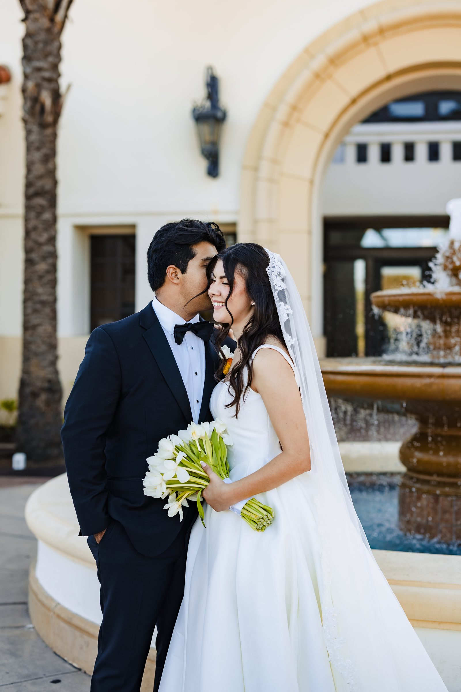 A kiss on the cheek beside a courtyard fountain