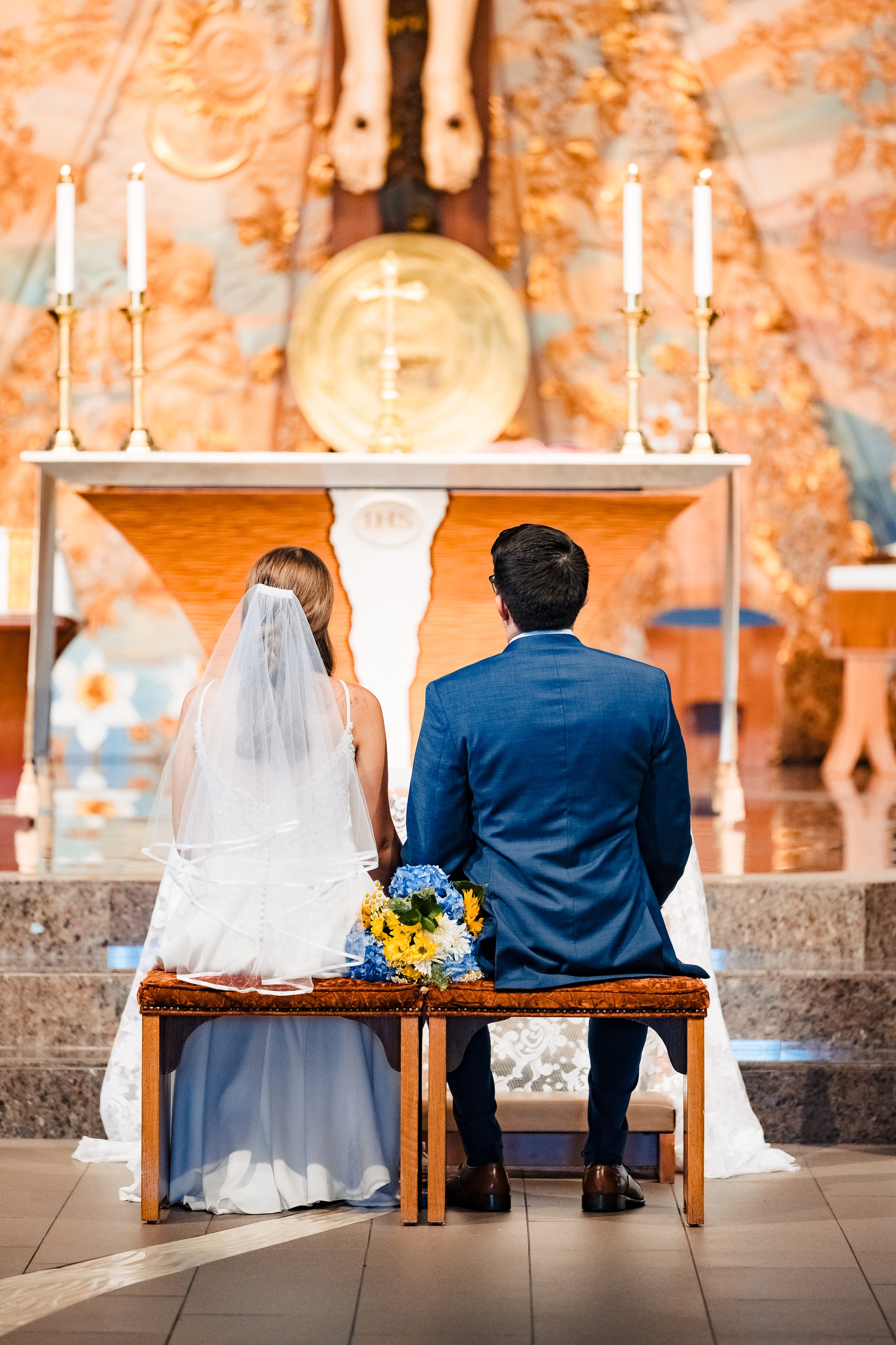 Guillermo and Annie at the altar beneath the carved corpus during their Nuptial Mass at Our Lady of Mount Carmel in San Diego