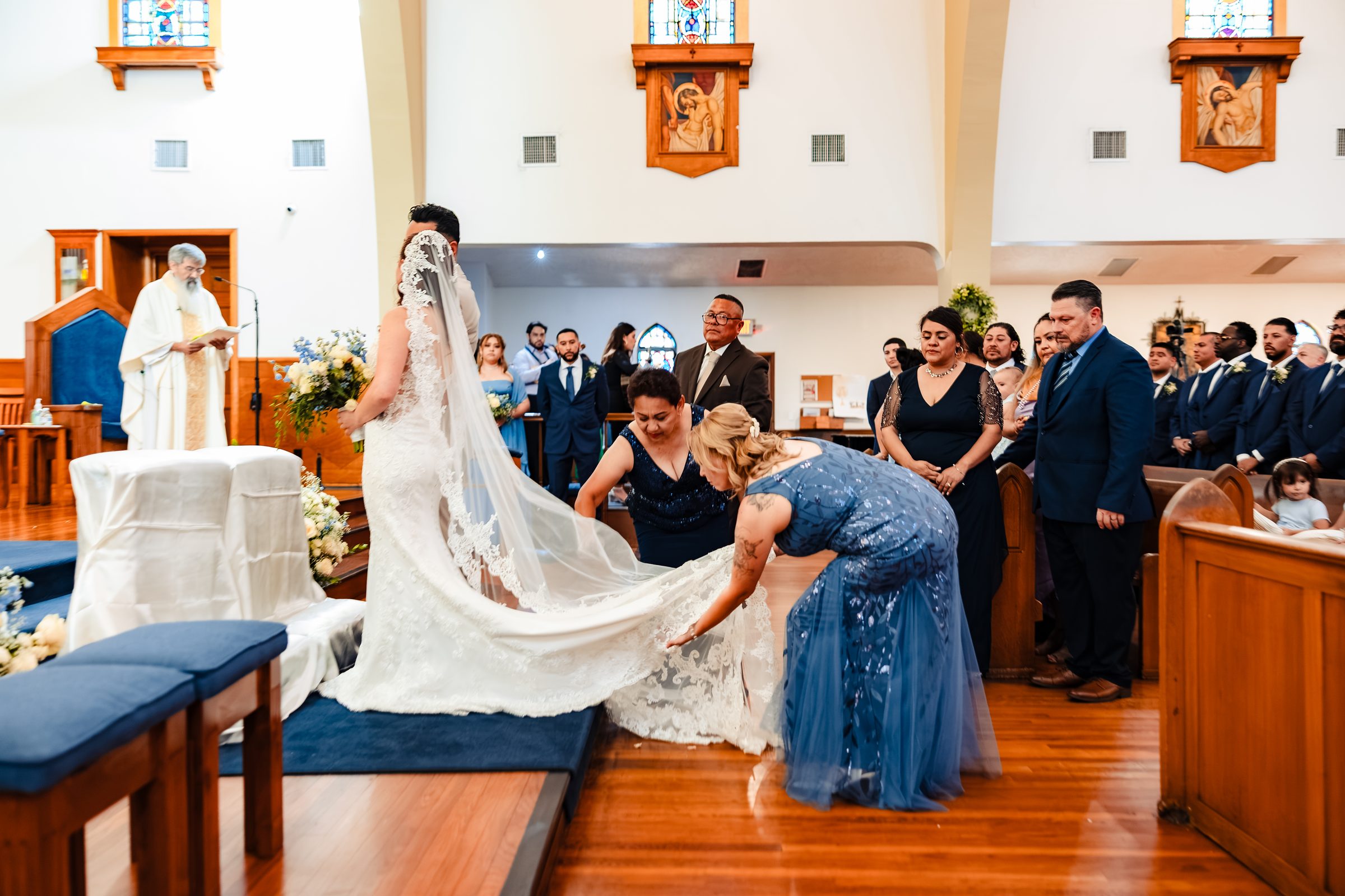 Family arranging the bride's train and veil at the altar