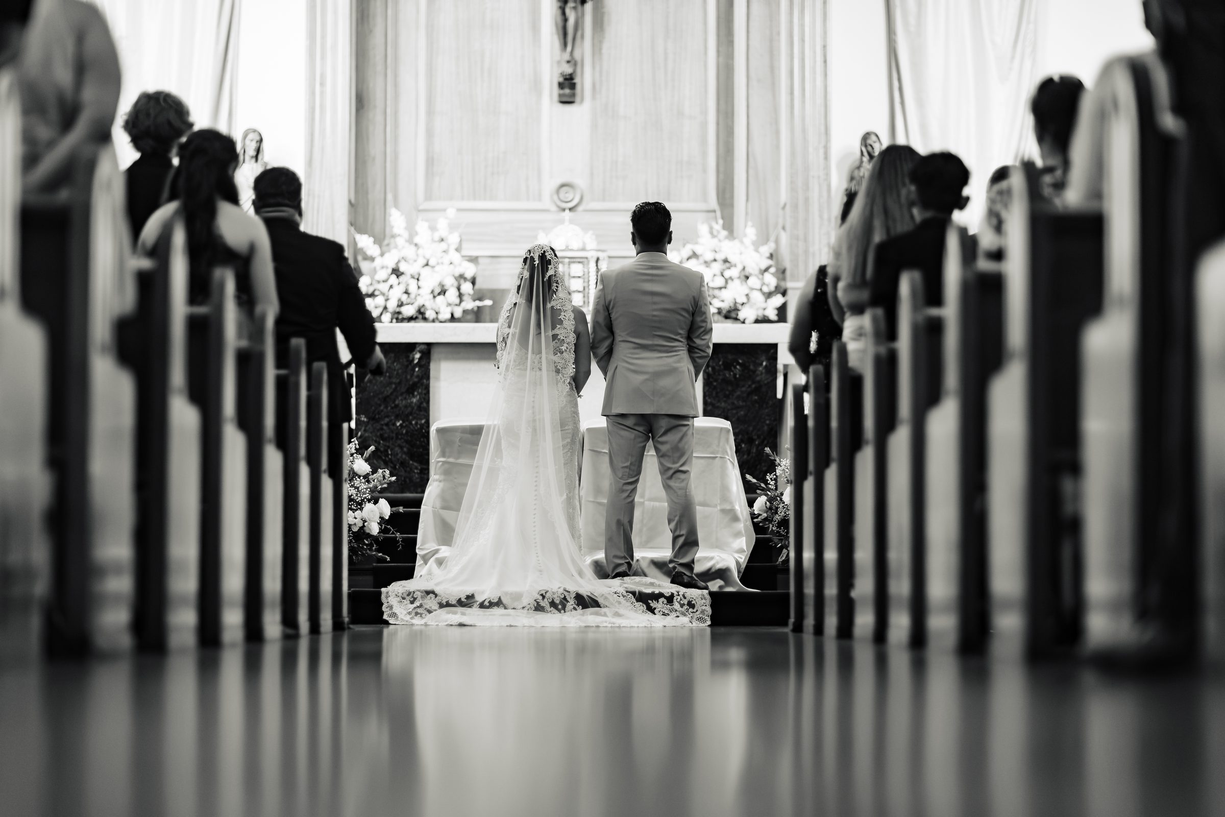 The couple kneeling at the altar, seen down the center aisle