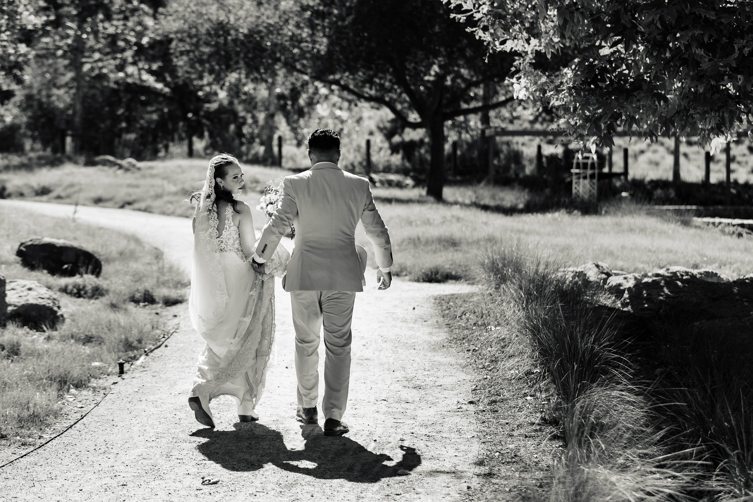 Black and white of the newlyweds walking a garden path