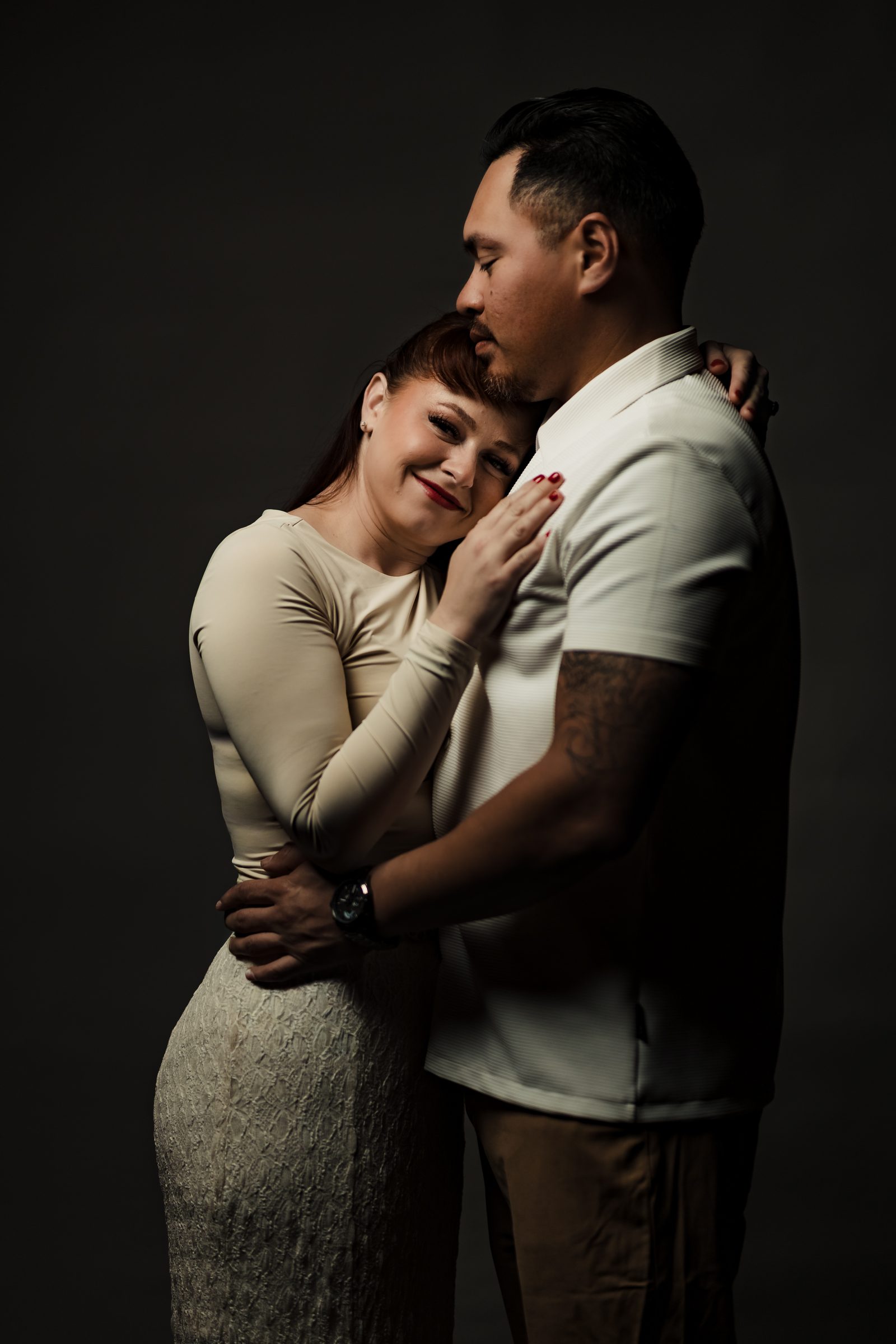 Isaac and Brittany embracing in a one-light studio engagement portrait