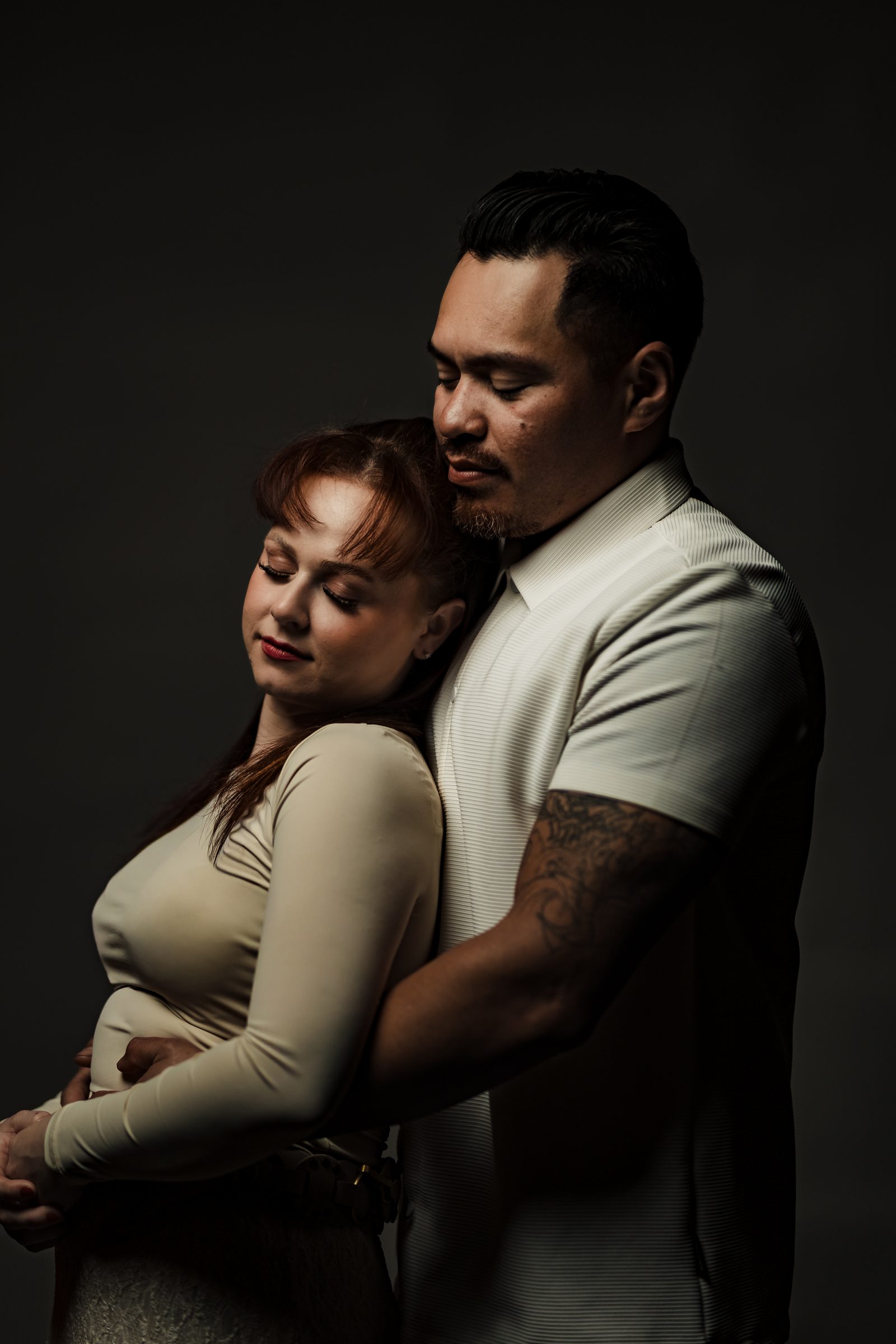 Isaac holding Brittany from behind against a dark backdrop