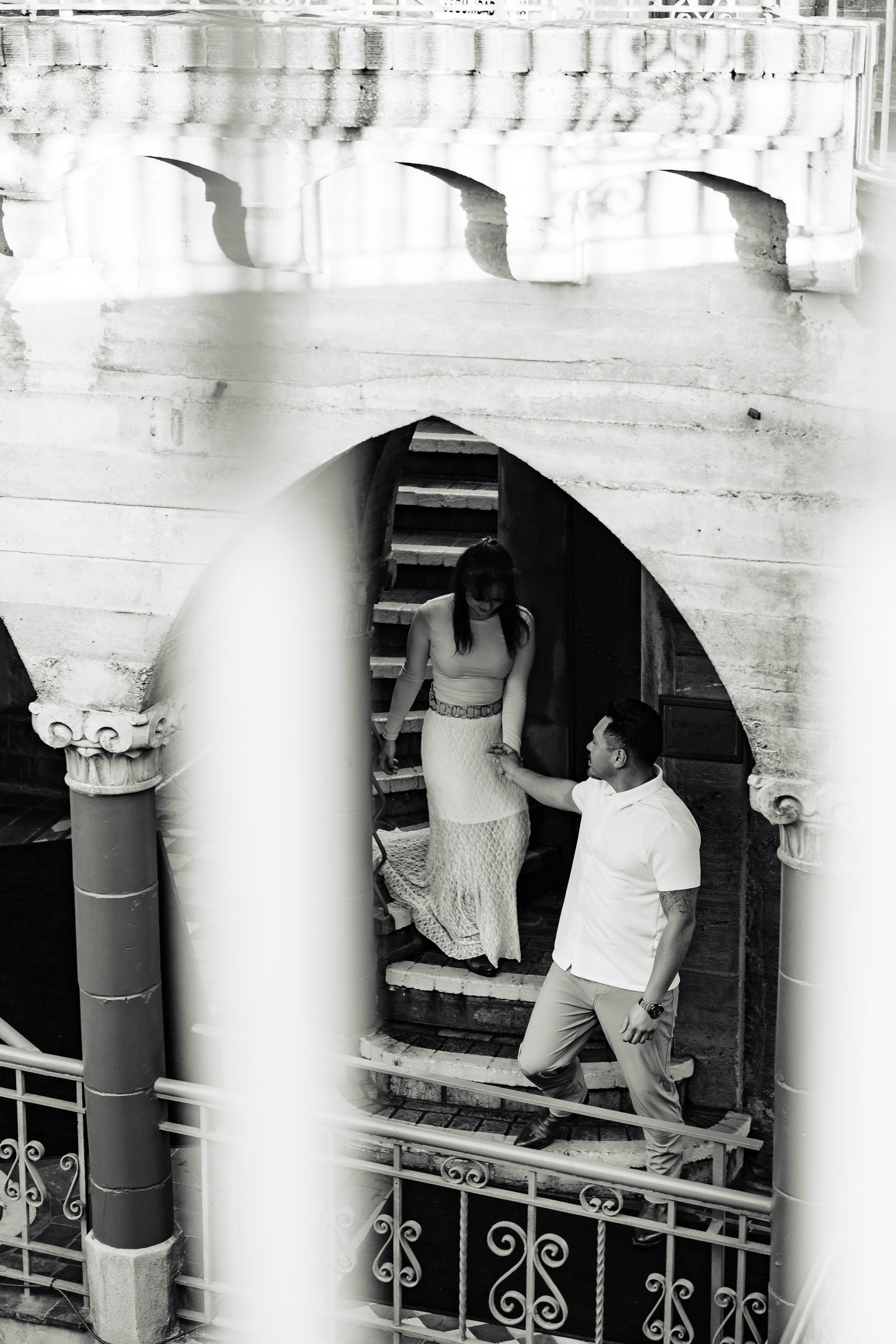 Black and white engagement portrait through a Mission Inn archway