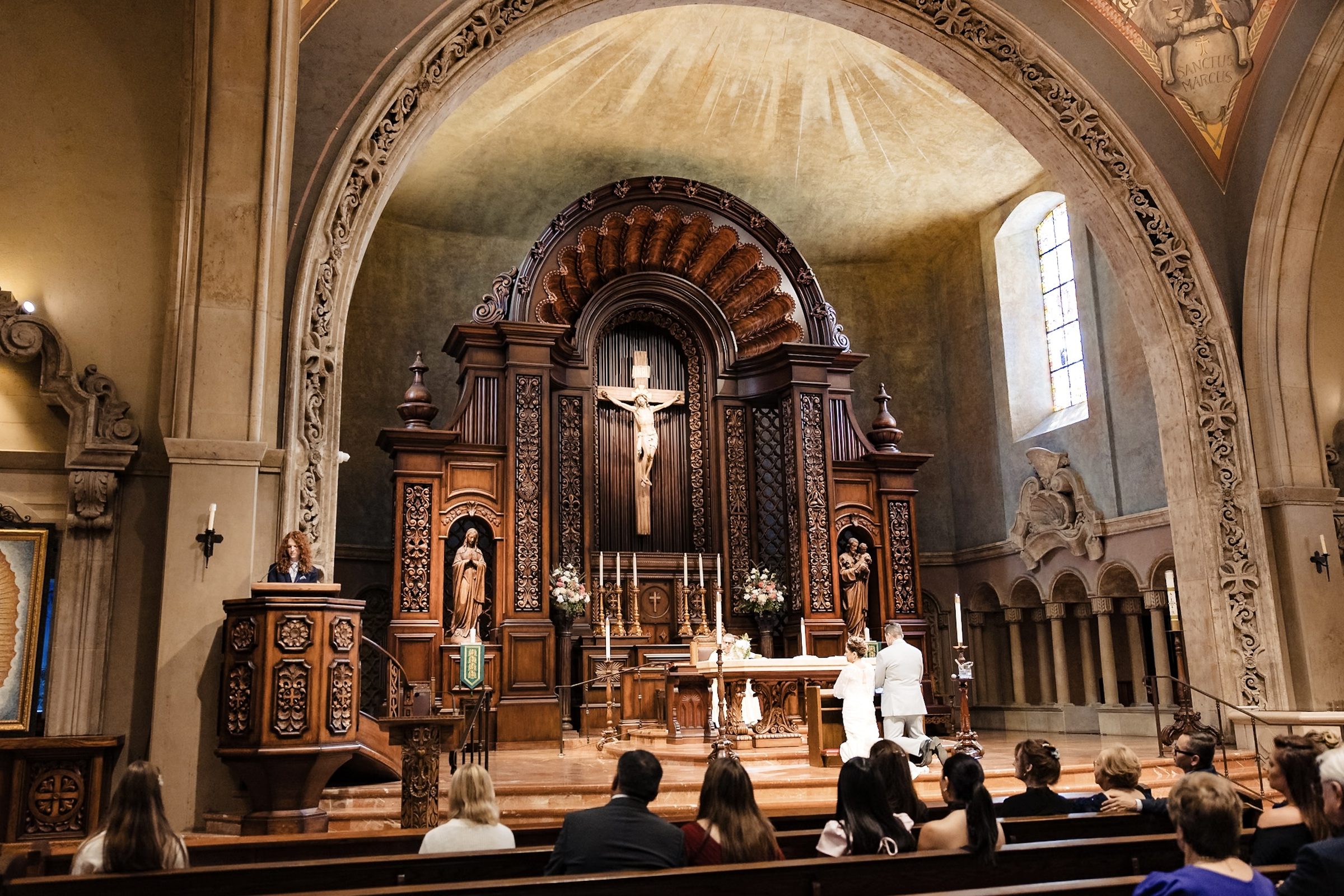 A reading from the carved pulpit as the couple kneels at the altar