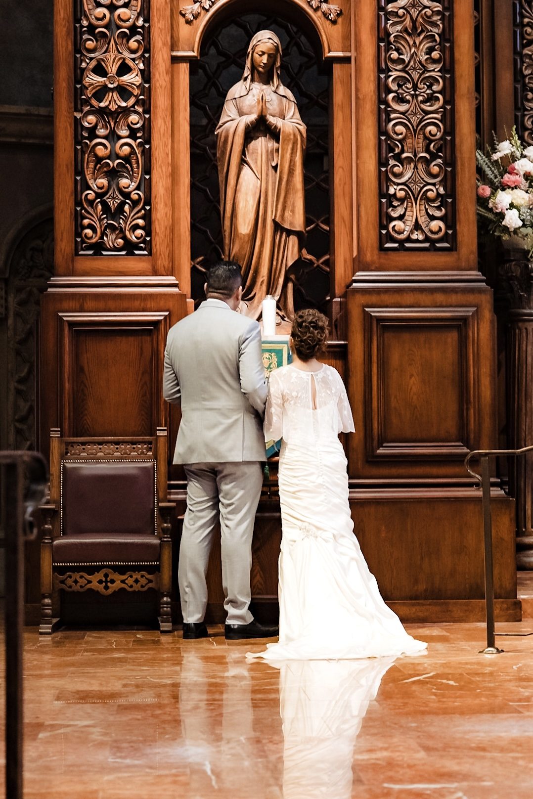Joe and Victoria praying before the carved statue of Our Lady