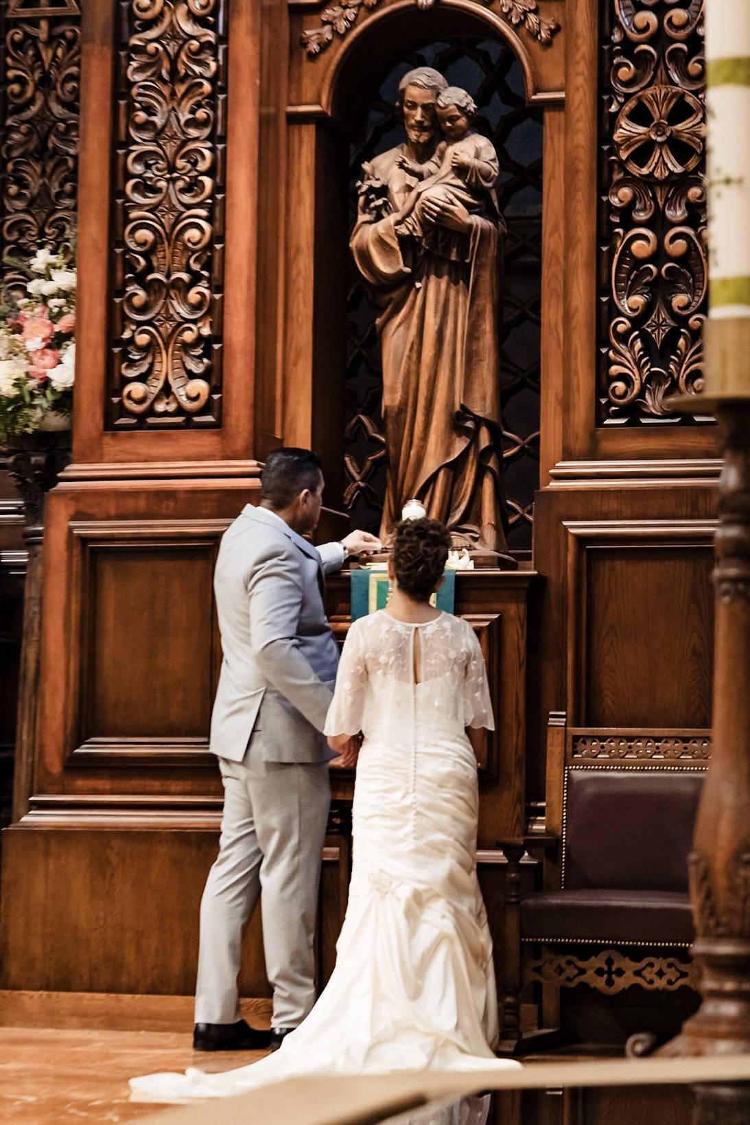 Joe lighting a candle before St. Joseph holding the Child Jesus