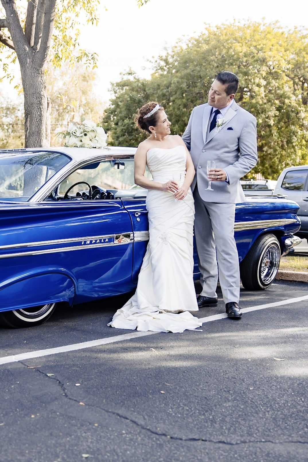 Joe and Victoria leaning on a blue lowrider Impala