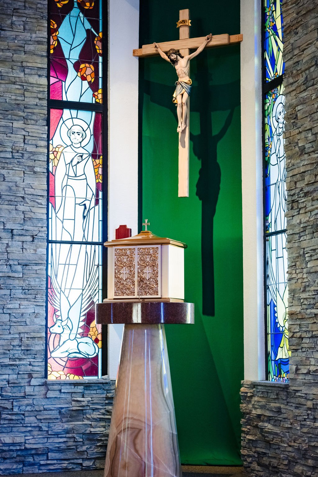 The crucifix above the tabernacle against green and stacked stone at St. Albert the Great