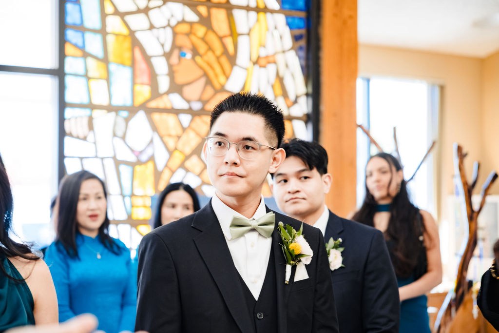 Vincent waiting with his groomsmen beneath the stained glass before the Mass