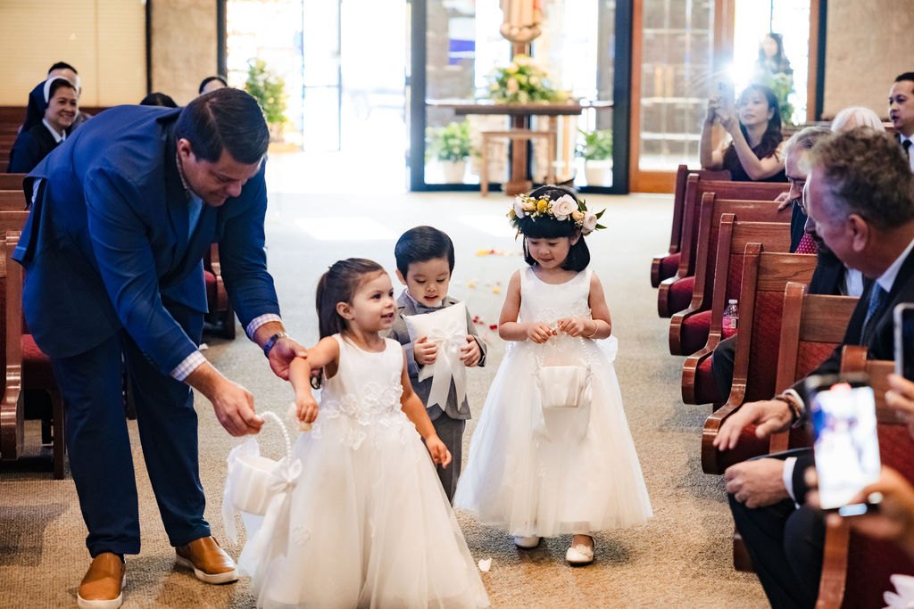 A groomsman guiding the flower girls down the aisle