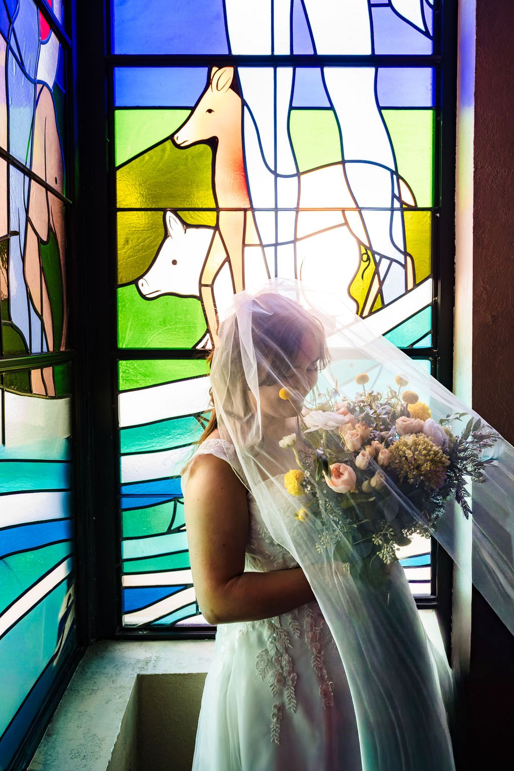 Ginger beneath the veil in front of colorful stained glass